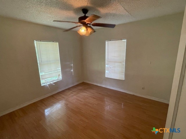 spare room featuring a textured ceiling, hardwood / wood-style flooring, and ceiling fan