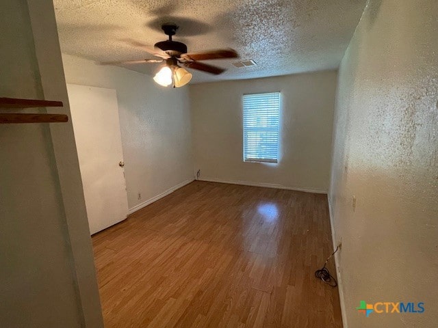 unfurnished room with a textured ceiling, light hardwood / wood-style flooring, and ceiling fan