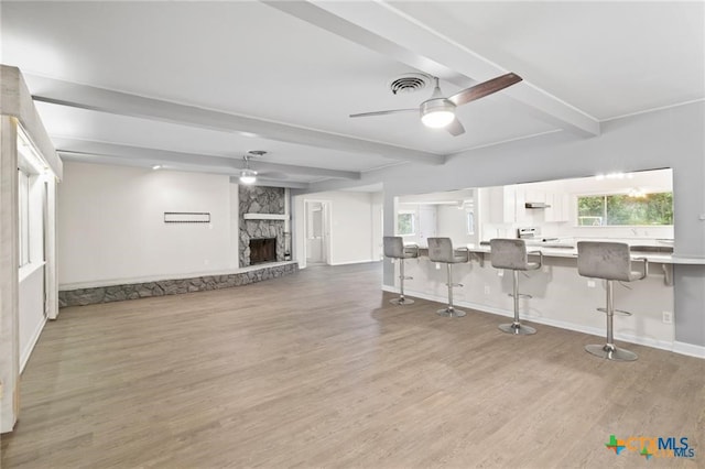 interior space featuring beam ceiling, a breakfast bar, white cabinets, and light hardwood / wood-style flooring