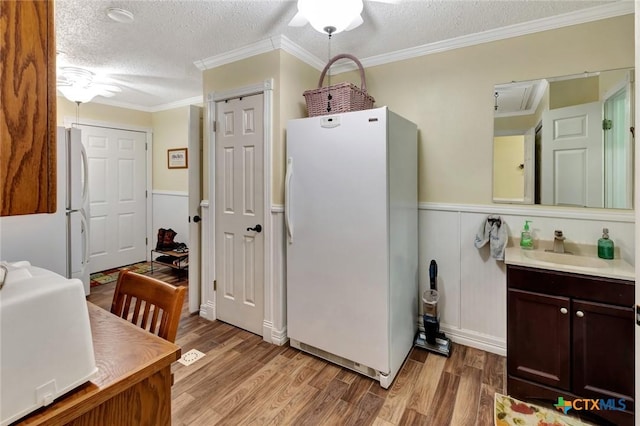 kitchen with ornamental molding, dark brown cabinets, a textured ceiling, sink, and white refrigerator