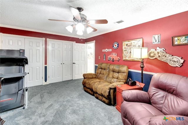 living room with carpet, ceiling fan, ornamental molding, and a textured ceiling