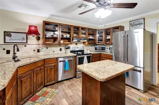 kitchen featuring appliances with stainless steel finishes, ornamental molding, a textured ceiling, sink, and light hardwood / wood-style floors