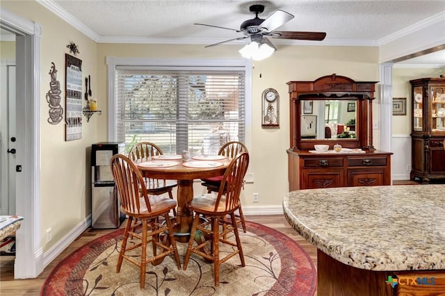 dining room with ceiling fan, crown molding, a textured ceiling, and light hardwood / wood-style flooring