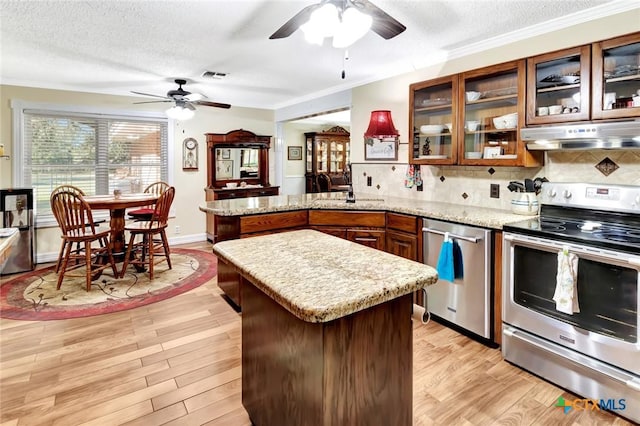 kitchen featuring a textured ceiling, backsplash, light wood-type flooring, and stainless steel appliances