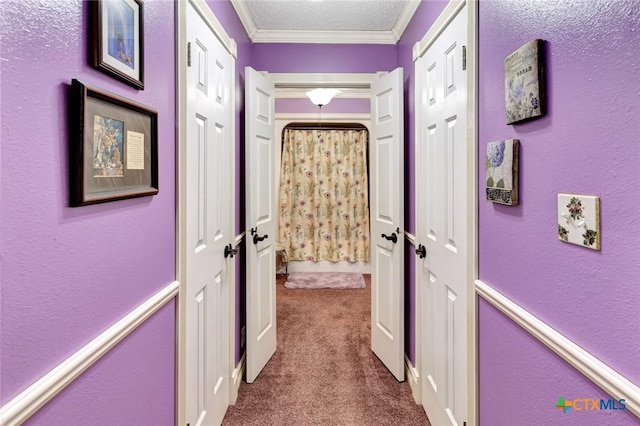 hall featuring a textured ceiling, ornamental molding, and carpet floors