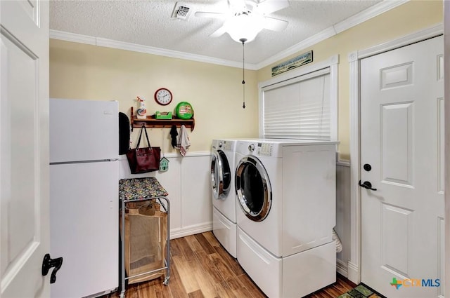 clothes washing area featuring washer and clothes dryer, ceiling fan, wood-type flooring, and a textured ceiling