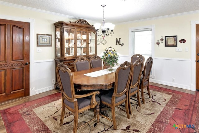 dining room with a textured ceiling, dark hardwood / wood-style floors, ornamental molding, and a notable chandelier