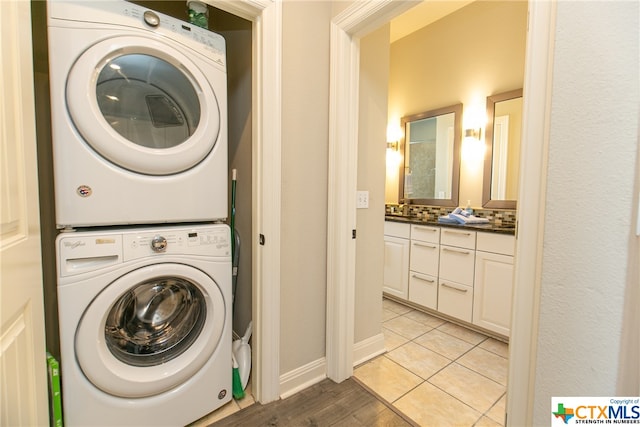 clothes washing area with stacked washer and clothes dryer and light tile patterned floors