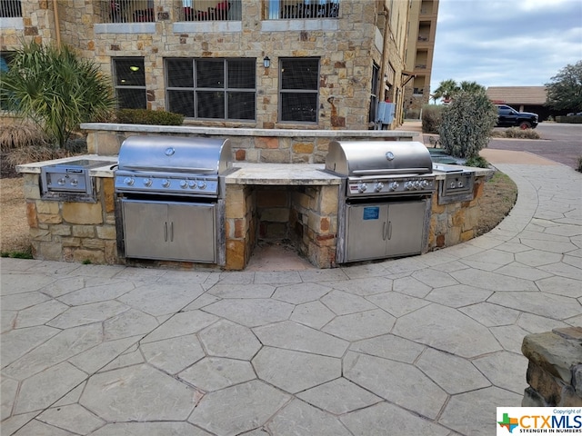 view of patio with area for grilling and a balcony