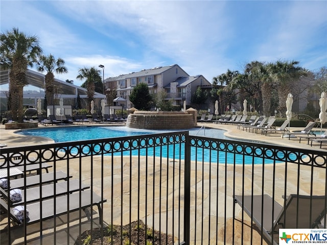 view of swimming pool with pool water feature and a patio