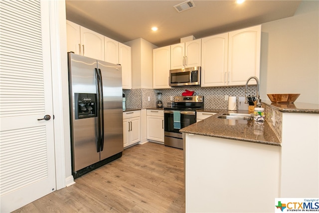 kitchen with stainless steel appliances, light wood-type flooring, sink, white cabinets, and kitchen peninsula