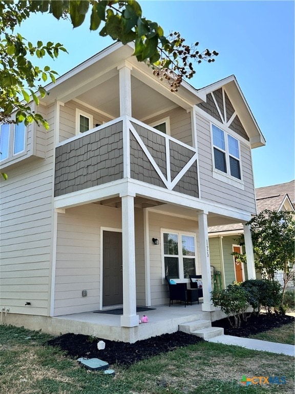 rear view of property with a balcony and covered porch