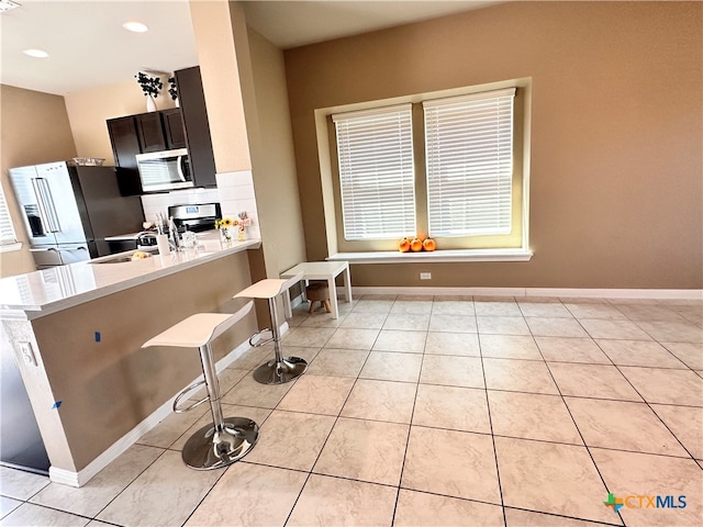 kitchen with dark brown cabinets, kitchen peninsula, stainless steel appliances, and a breakfast bar area