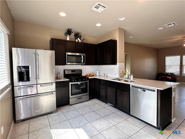 125 Duck Creek Trl, San Marcos, TX 78666 - kitchen featuring stainless steel appliances, a sink, light tile patterned floors, tasteful backsplash, and light countertops