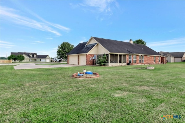 46 Bluestem St, Victoria, TX 77904 - rear view of house with brick siding, a sunroom, driveway, a yard, and a garage