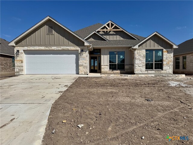 view of front of house with board and batten siding, driveway, a shingled roof, and a garage