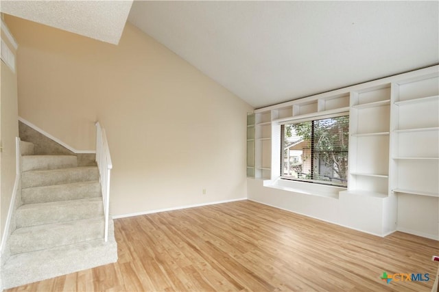 unfurnished living room with hardwood / wood-style flooring and vaulted ceiling