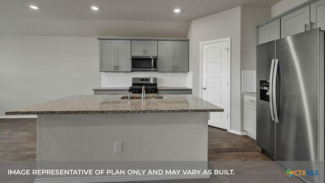 kitchen featuring stainless steel appliances, gray cabinets, light stone countertops, and a kitchen island with sink