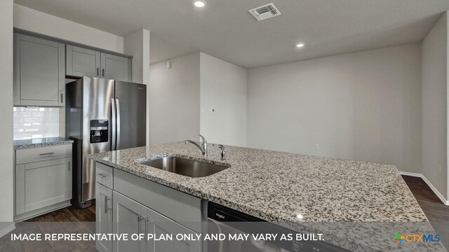 kitchen with tasteful backsplash, sink, stainless steel fridge, and light stone countertops