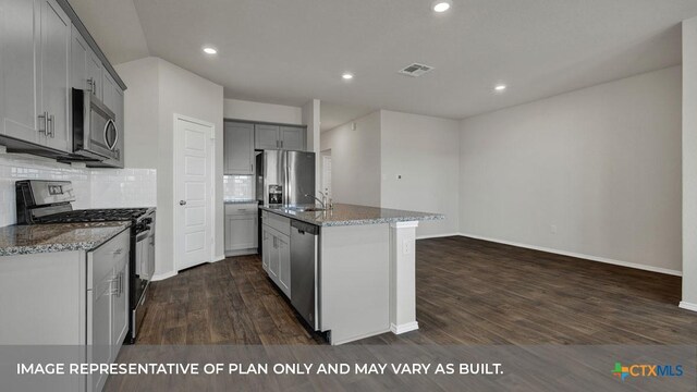 kitchen featuring gray cabinetry, a center island with sink, appliances with stainless steel finishes, dark hardwood / wood-style flooring, and backsplash