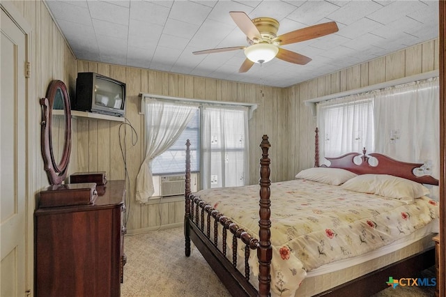 bedroom featuring ceiling fan, cooling unit, light carpet, and wooden walls