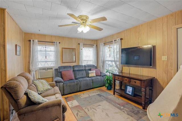 living room featuring cooling unit, wood walls, and ceiling fan