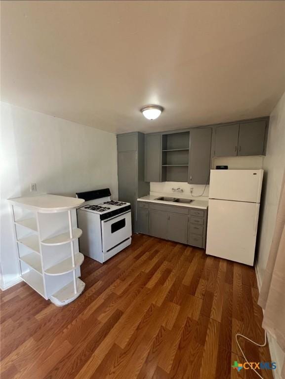 kitchen featuring open shelves, a sink, gray cabinetry, and white appliances