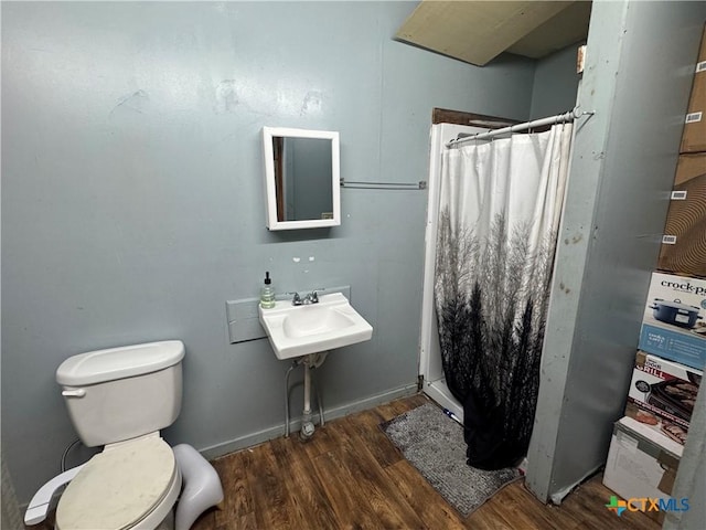 400 Grimes St, Cuero, TX 77954 - full bathroom with wood finished floors, toilet, curtained shower, and a sink