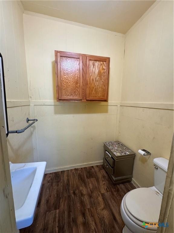 400 Grimes St, Cuero, TX 77954 - bathroom featuring wood finished floors, toilet, and a decorative wall