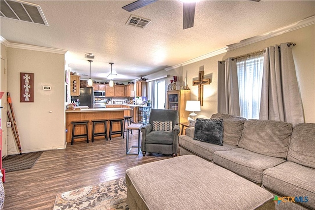 living room with ceiling fan, dark wood-type flooring, ornamental molding, and a textured ceiling