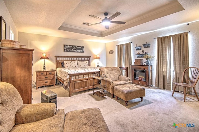 bedroom featuring ornamental molding, light carpet, a textured ceiling, and a tray ceiling