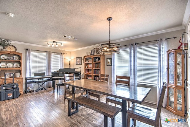 dining space featuring crown molding, hardwood / wood-style flooring, and a textured ceiling