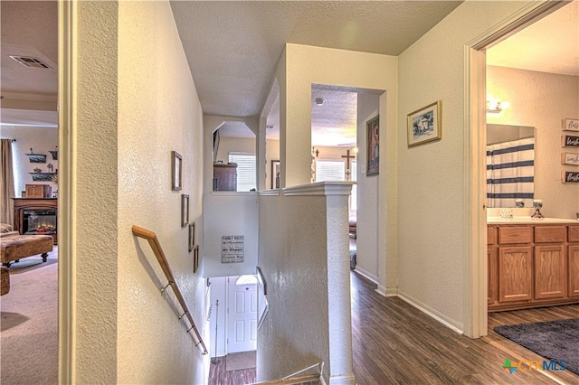 corridor featuring sink, dark hardwood / wood-style floors, and a textured ceiling