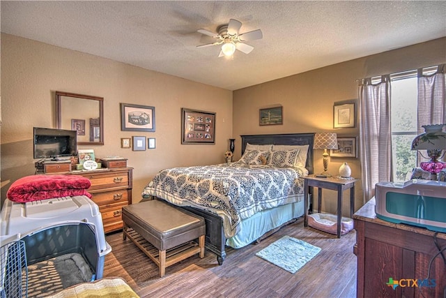 bedroom with ceiling fan, wood-type flooring, and a textured ceiling