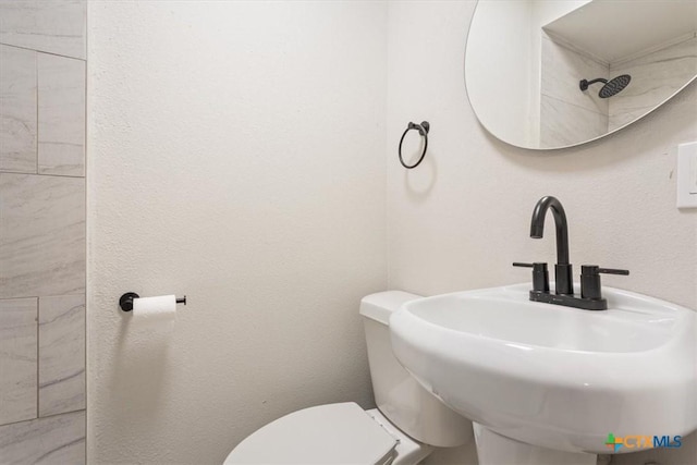 bathroom featuring a textured wall, a sink, and toilet