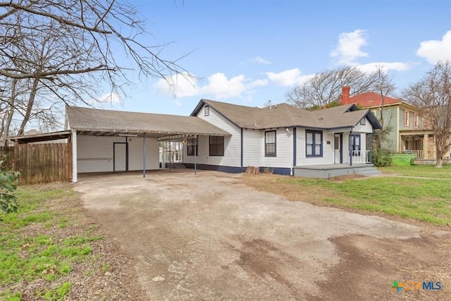 view of front of property with fence, concrete driveway, a carport, a chimney, and a front yard