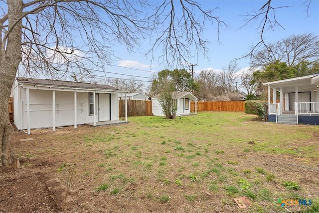 view of yard with an outbuilding, a storage shed, covered porch, and a fenced backyard