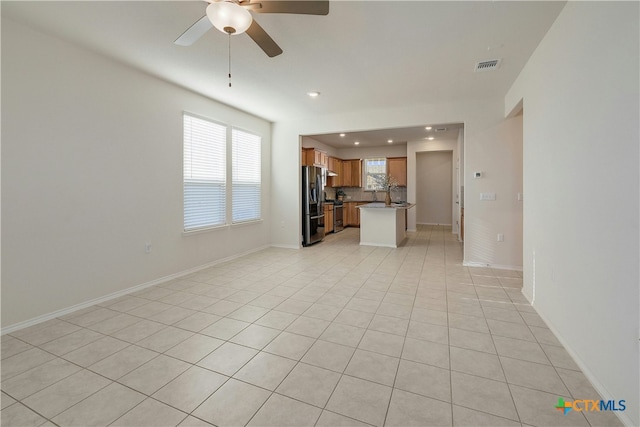 unfurnished living room featuring light tile patterned flooring, ceiling fan, and sink