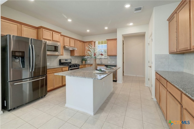 kitchen featuring a kitchen island, appliances with stainless steel finishes, light tile patterned floors, and light stone counters