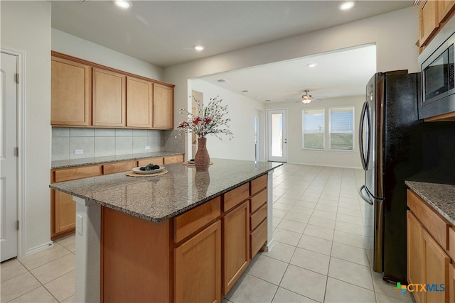 kitchen featuring dark stone countertops, backsplash, a center island, and appliances with stainless steel finishes