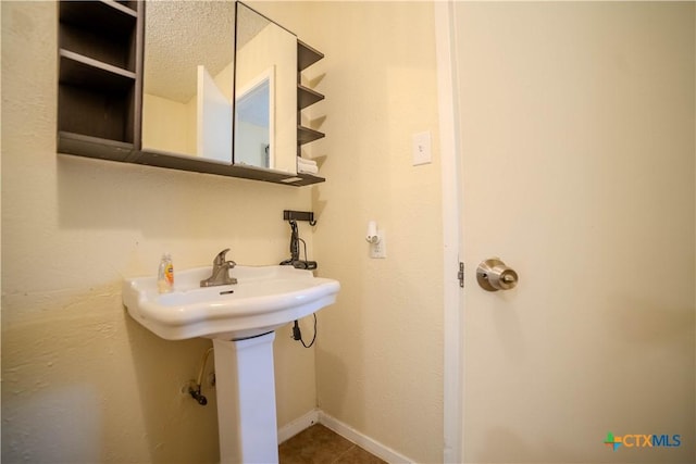 bathroom featuring baseboards, a sink, and tile patterned floors