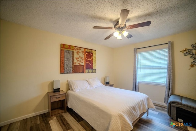 bedroom with a ceiling fan, a textured ceiling, baseboards, and wood finished floors