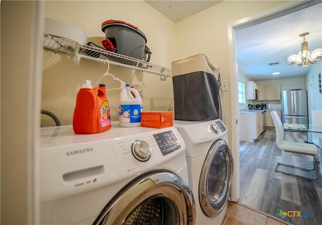 clothes washing area with a notable chandelier, visible vents, light wood-style flooring, laundry area, and independent washer and dryer