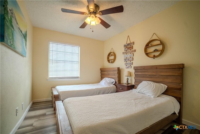 bedroom with a ceiling fan, baseboards, a textured ceiling, and wood finished floors