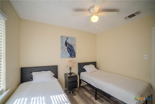 bedroom featuring visible vents, ceiling fan, a textured ceiling, and wood finished floors