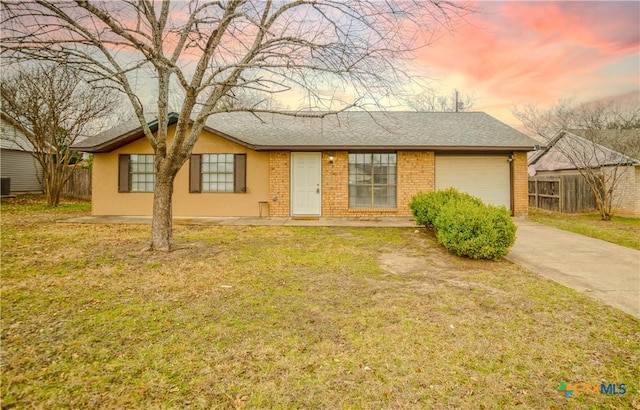 ranch-style home with brick siding, fence, a garage, driveway, and a front lawn