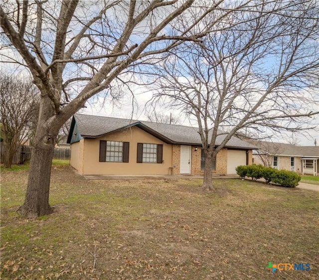 ranch-style home featuring a shingled roof, a front yard, fence, and brick siding