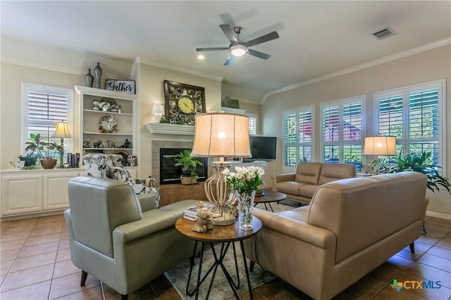 1320 Daisy Ln, Temple, TX 76502 - living room featuring crown molding, ceiling fan, light tile patterned floors, and a tile fireplace