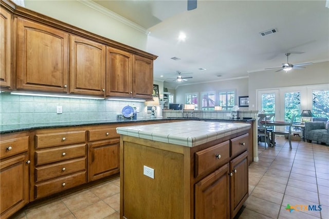 1320 Daisy Ln, Temple, TX 76502 - kitchen with a ceiling fan, light tile patterned floors, brown cabinetry, backsplash, and tile counters