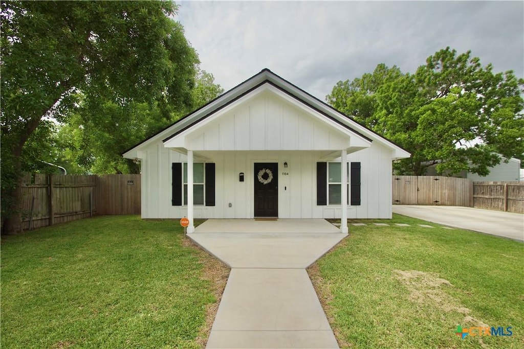 bungalow-style house with a front lawn, board and batten siding, fence, and a porch